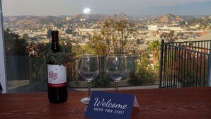 Una botella de vino, dos copas de vino y un cartel de bienvenida sobre una mesa con vistas a la ciudad.