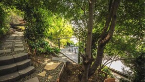 Un muelle de madera con escalones que bajan a un jardín con vista a una masa de agua.