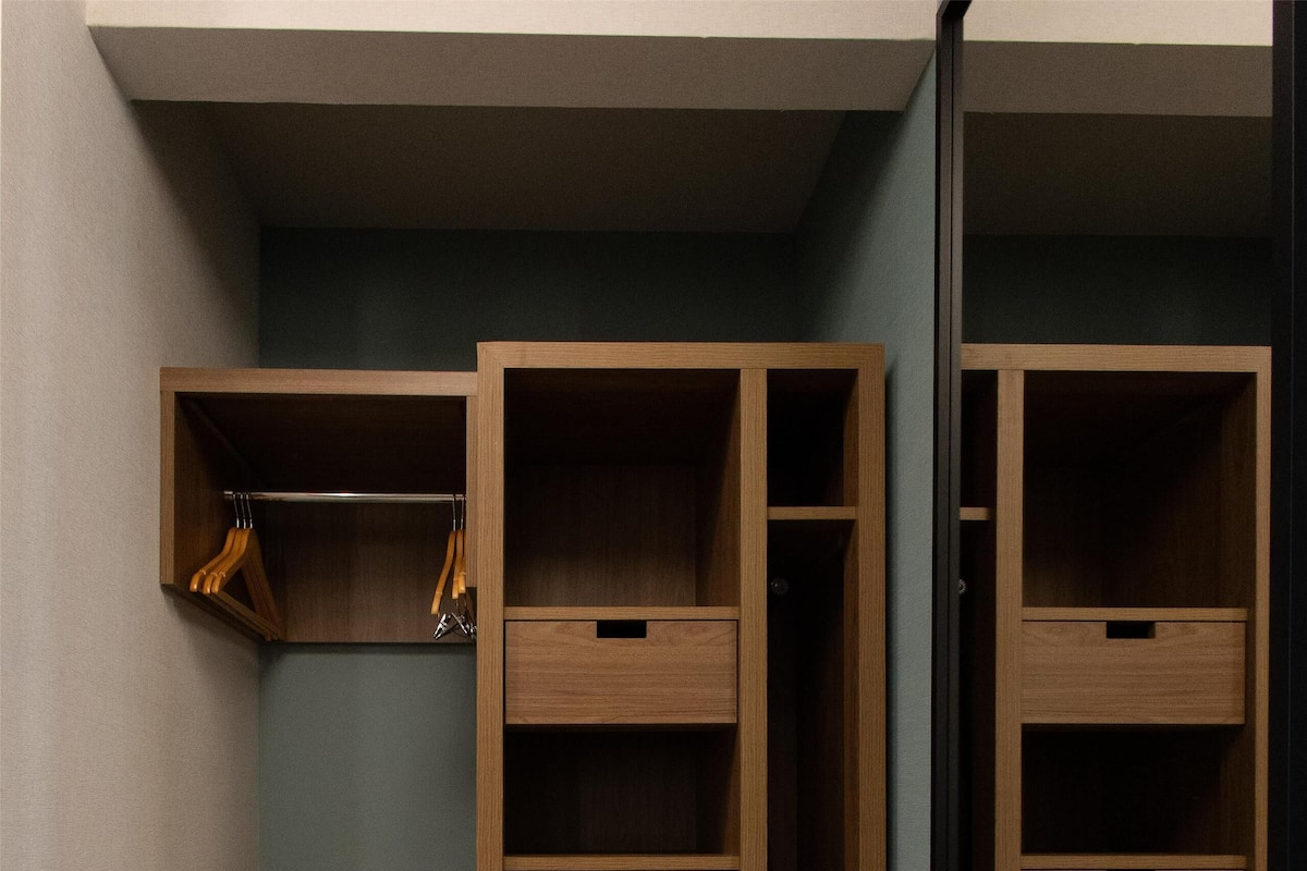 A closet with multiple wooden drawers and shelves, a mirror, and a wooden chair.