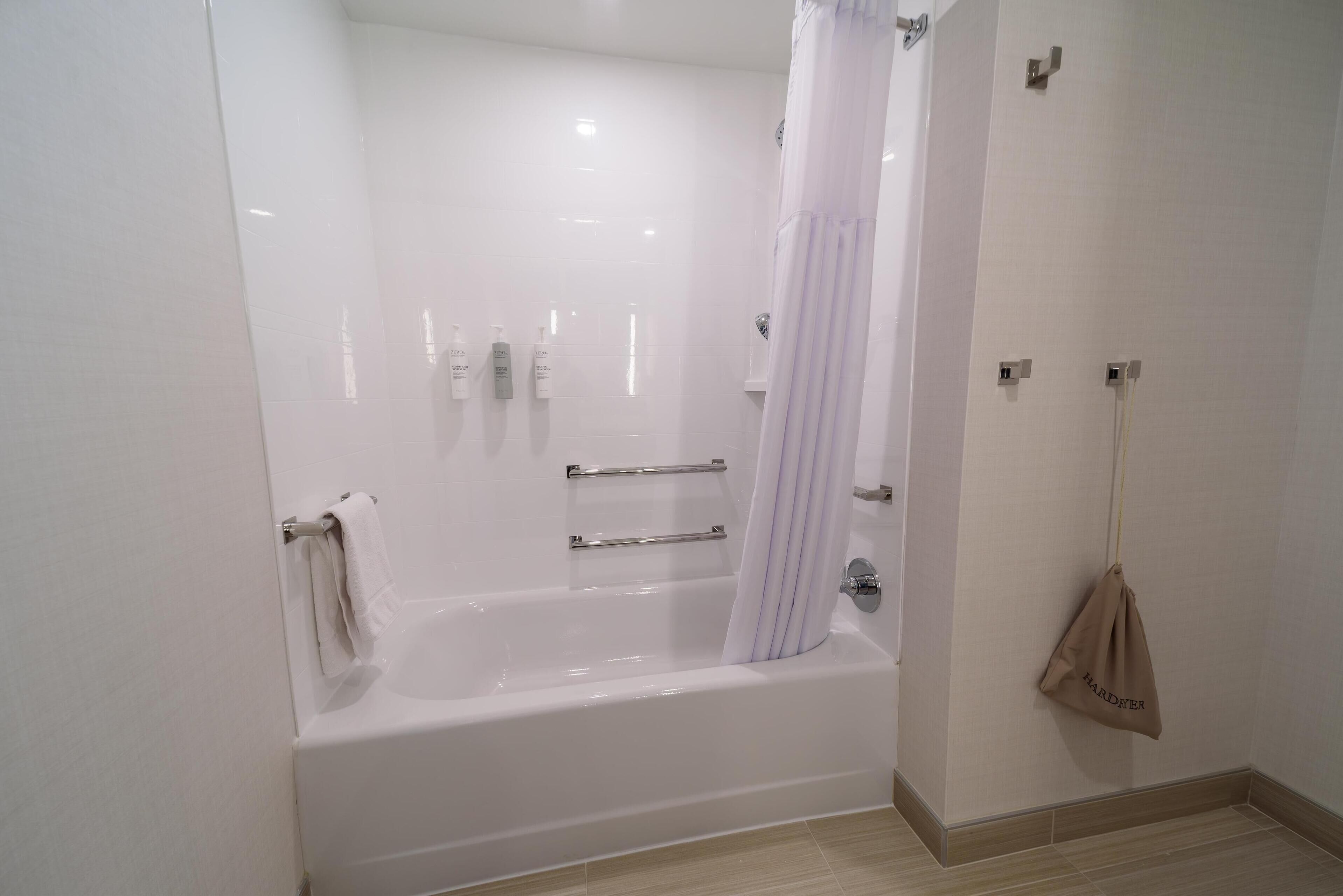 A modern bathroom with a bathtub, a shower curtain, and a towel rack.