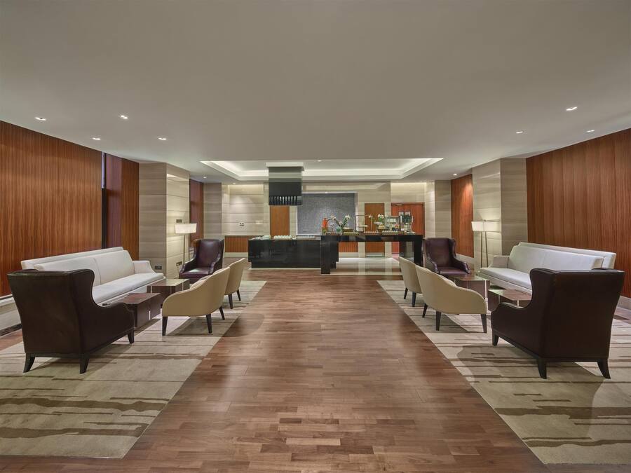 Een moderne lobby met een receptiebalie, banken en een centraal gedeelte met een decoratieve fontein.