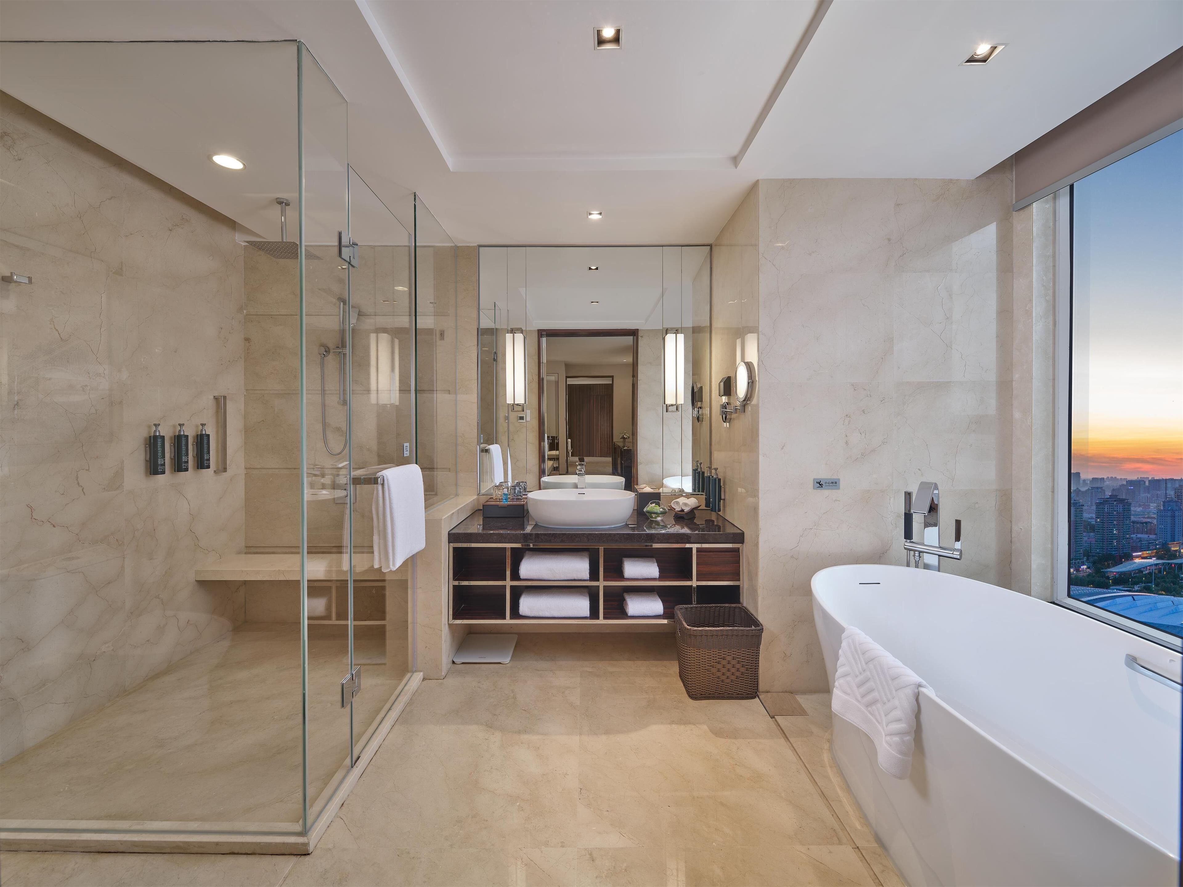 Un baño moderno con cabina de ducha de vidrio, un mueble de tocador amplio con lavamanos y una bañera.