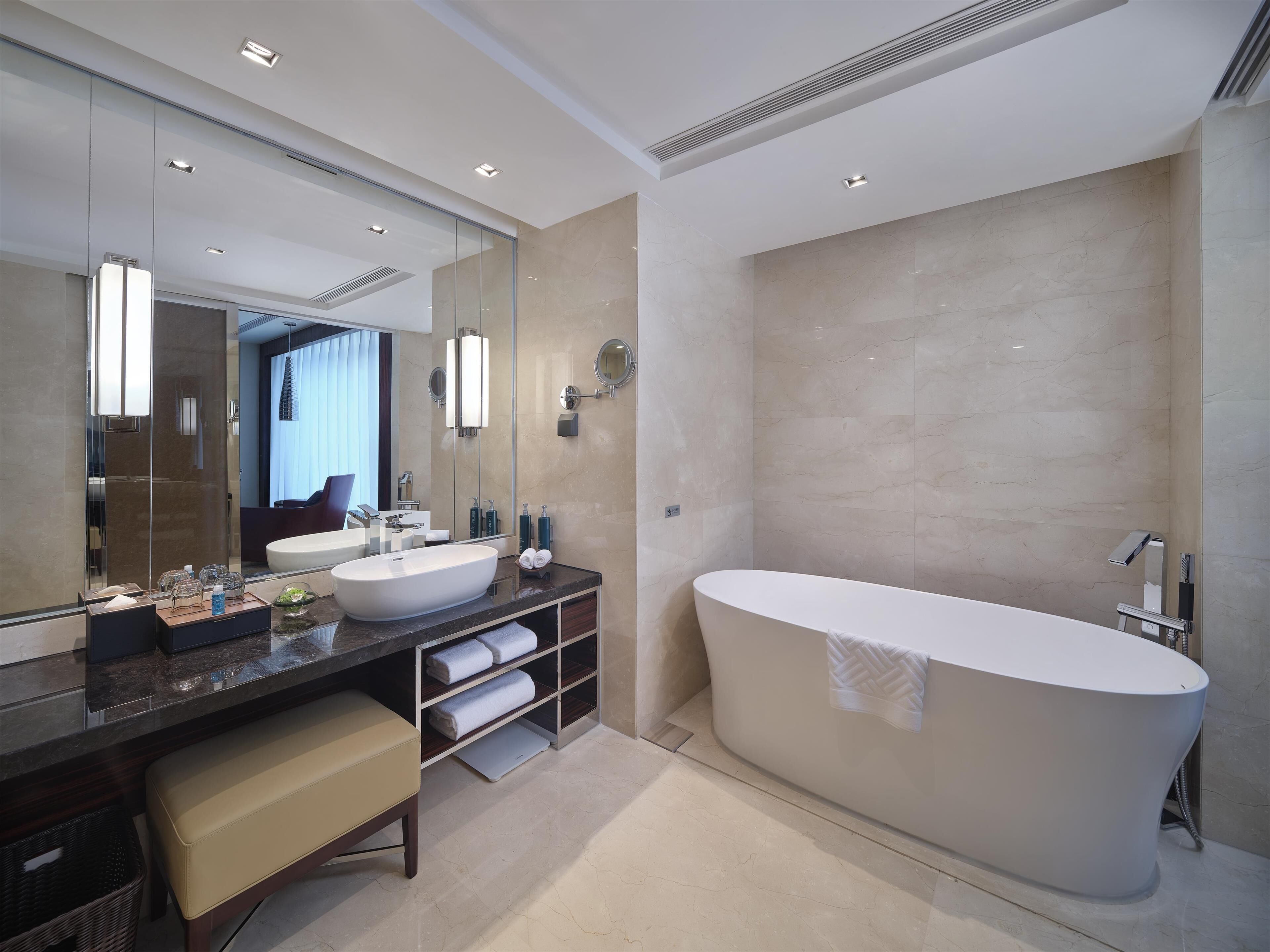Un baño moderno con una bañera independiente grande, un tocador con doble lavabo y un espejo amplio.