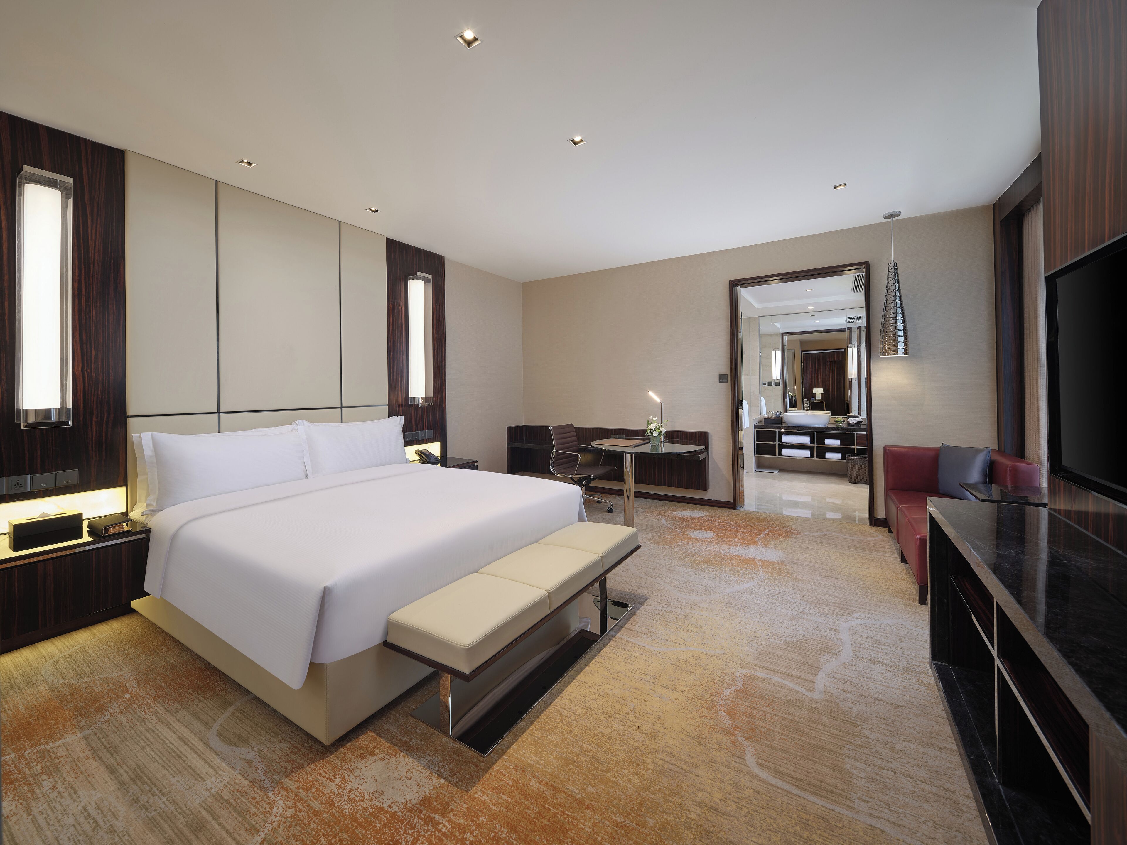 Una habitación de hotel moderna con una cama grande, un escritorio, un sofá y un televisor.