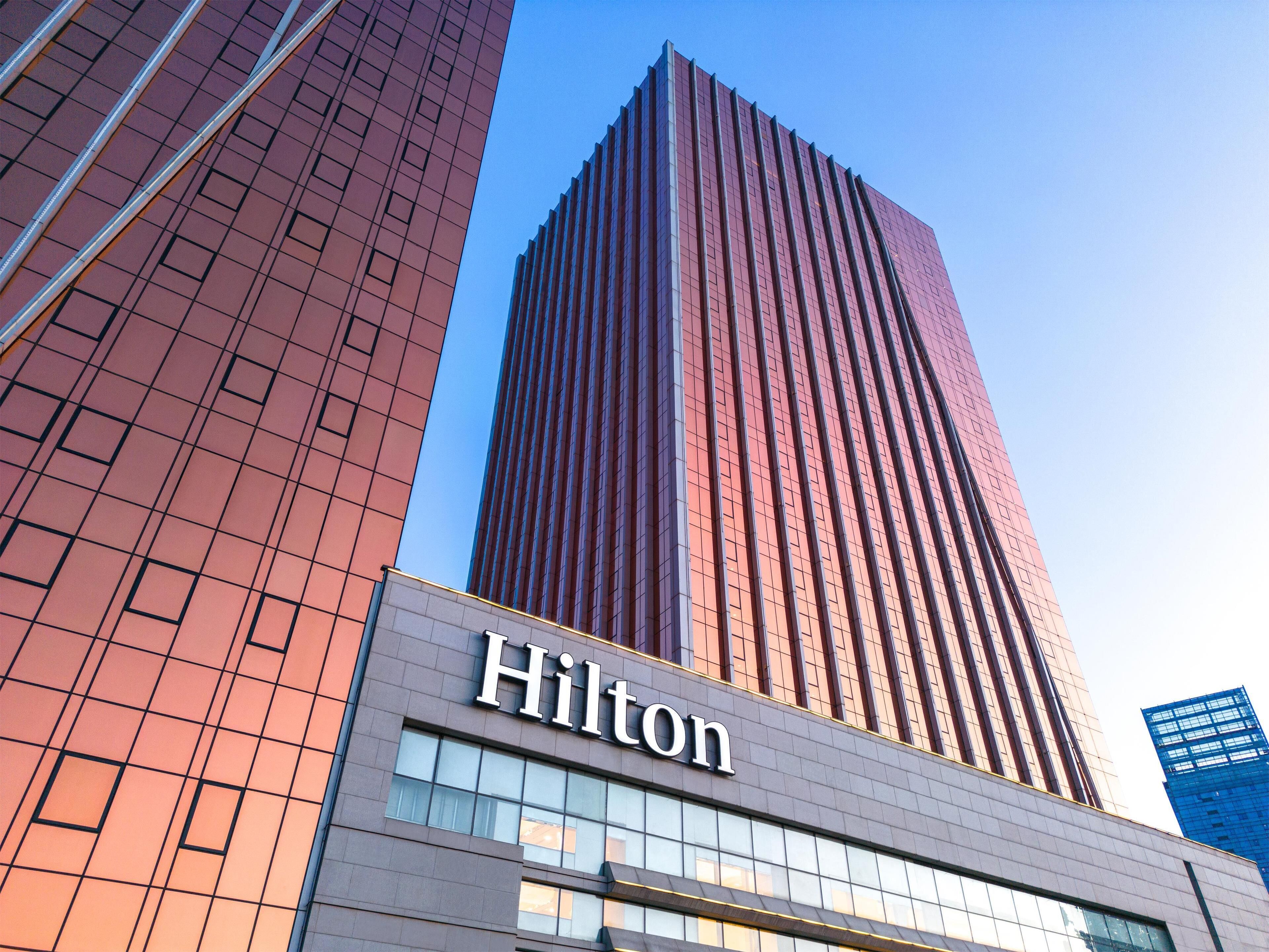 A Hilton hotel building with a modern glass facade and a prominent 'Hilton' sign.