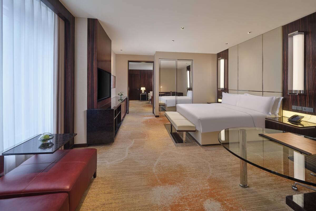 Ein modernes Hotelzimmer mit einem großen Bett, einem Schreibtisch, einem Fernseher und einer Sitzecke.