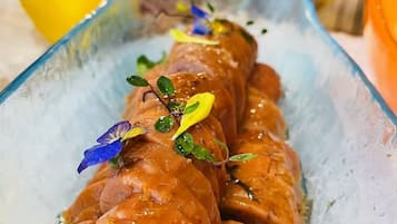 A glass dish with sliced salmon on ice, garnished with herbs and edible flowers.