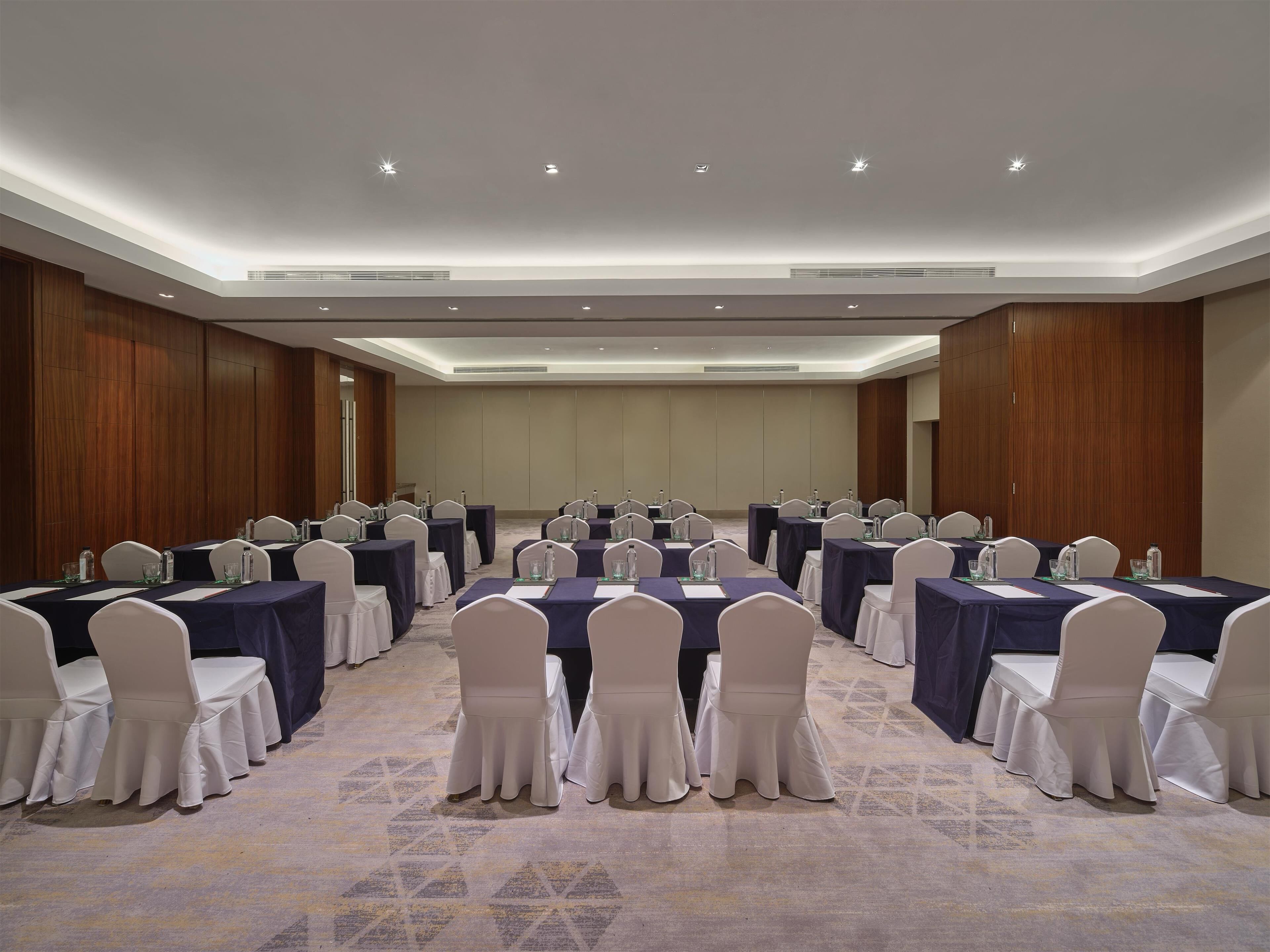 A conference room with multiple tables and chairs, equipped with water bottles and nameplates.