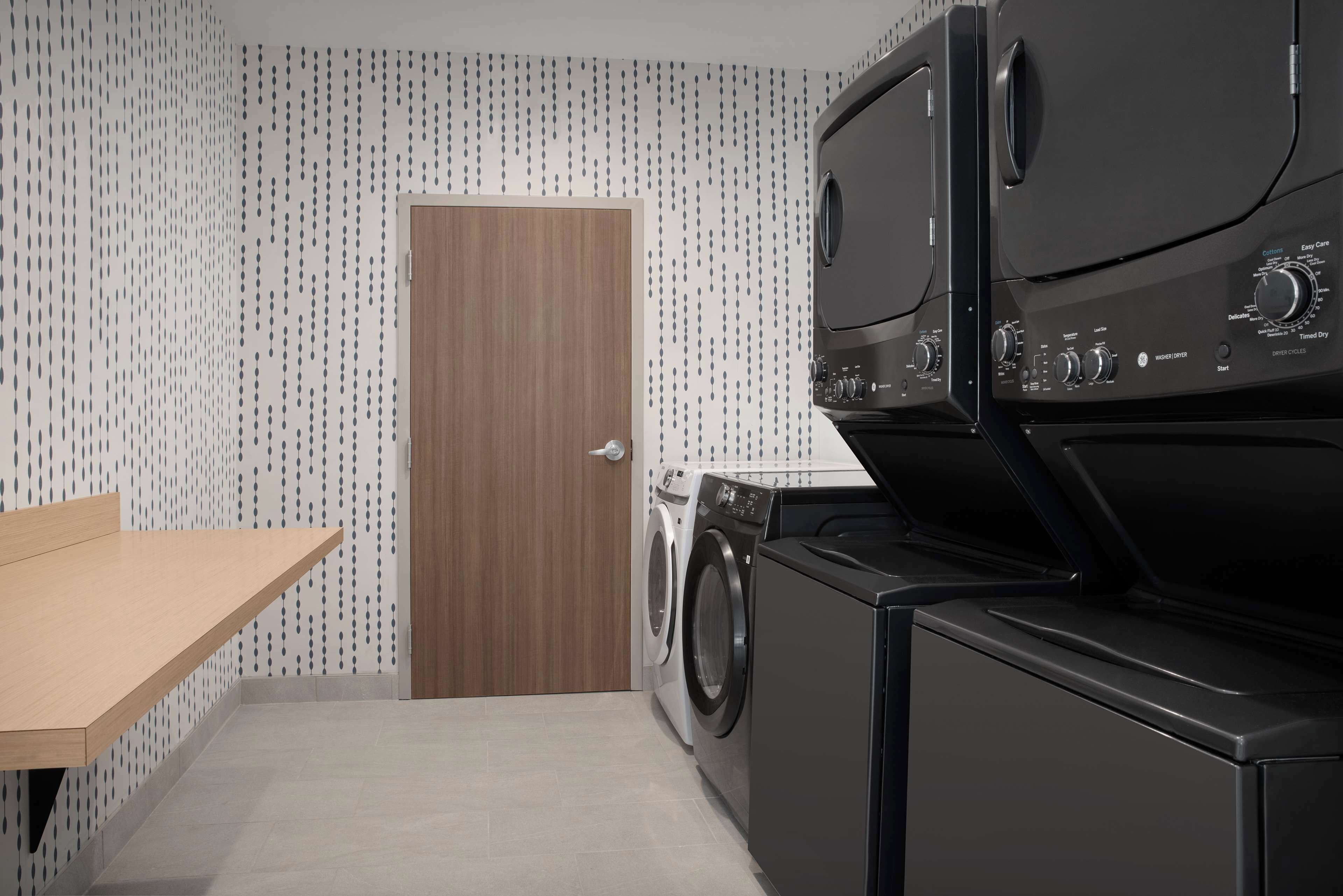 A compact laundry area with a washing machine, dryer, and a wooden door.