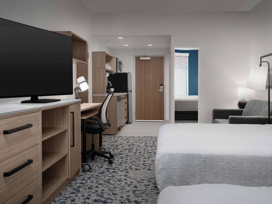 Una habitación de hotel con una cama, un escritorio con ordenador, televisión y una silla.