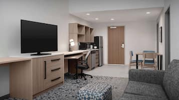 Un espace de vie moderne et compact, doté d’un téléviseur à écran plat, d’une kitchenette, d’un canapé et d’un coin repas.