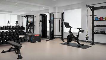 Ett modernt gym med olika typer av träningsutrustning, inklusive hantlar, en träningsbänk och en motionscykel.