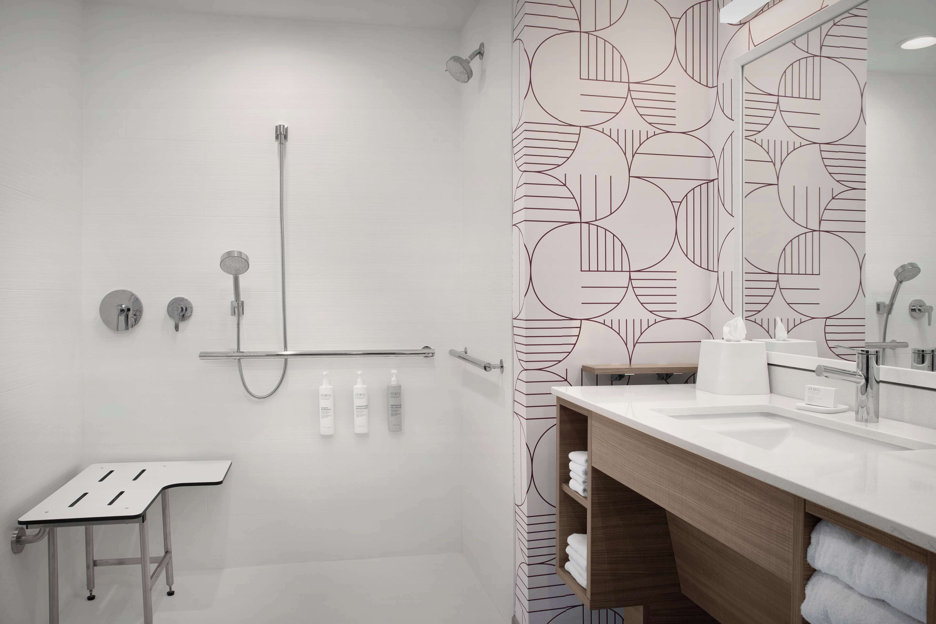 A modern bathroom with a shower, a sink, and a mirror.
