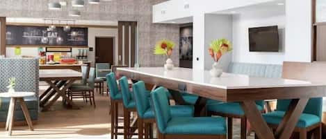 Un restaurante moderno con una barra alargada, sillas color turquesa e iluminación colgante.