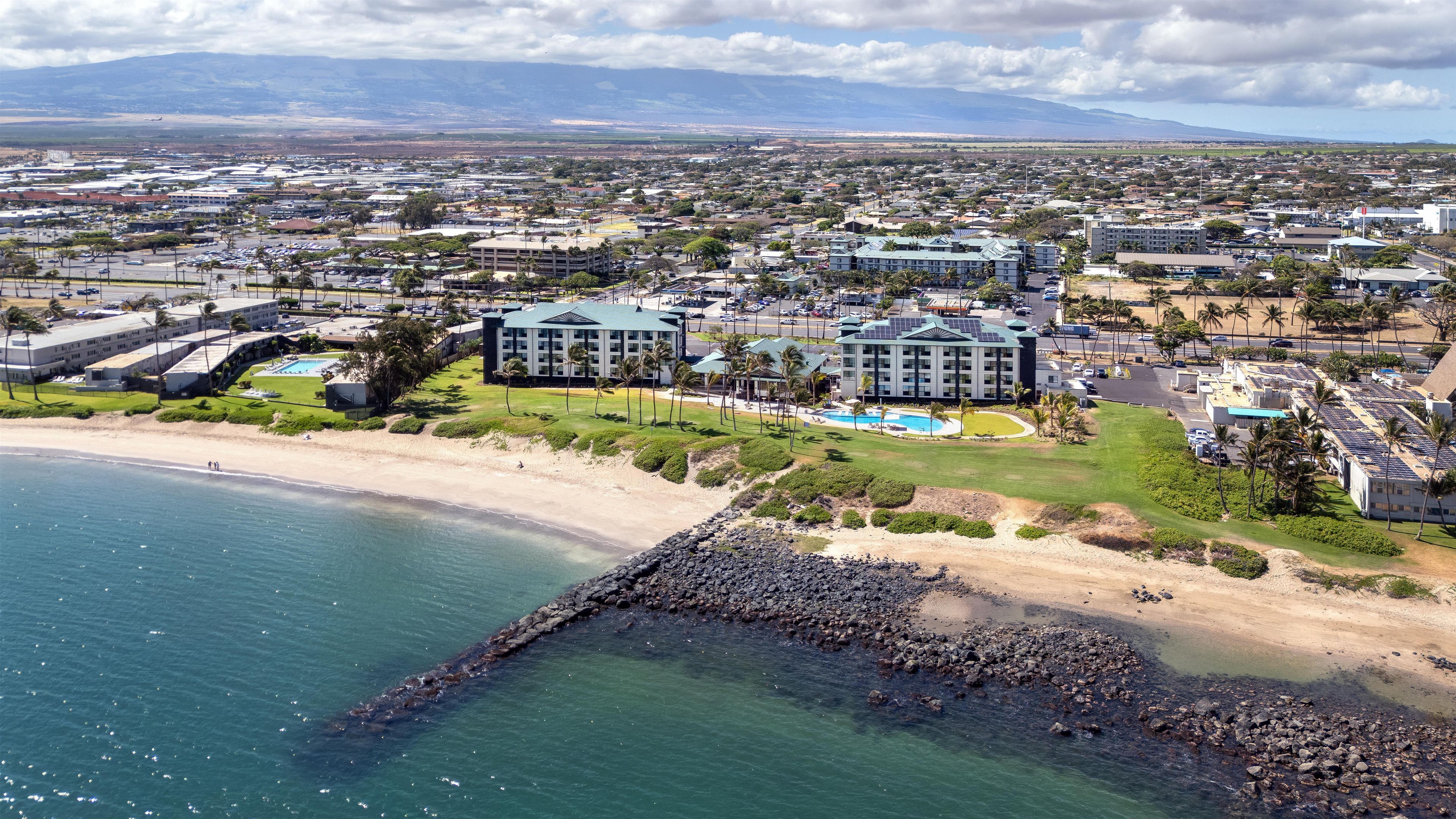 A coastal resort with multiple buildings, a beach, and a rocky shoreline.