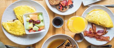 A breakfast table with various dishes including waffles, eggs, bacon, and fruit.