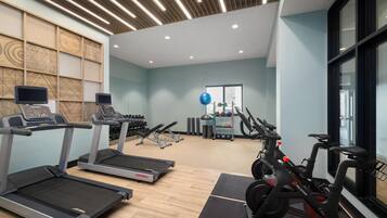 Une salle de sport équipée de tapis de course, d’un vélo elliptique et d’un vélo d’appartement.