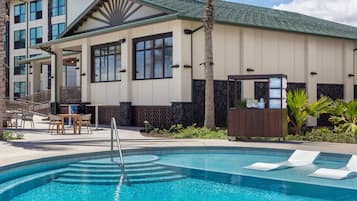 A hotel with a swimming pool, outdoor seating, and a stone facade.