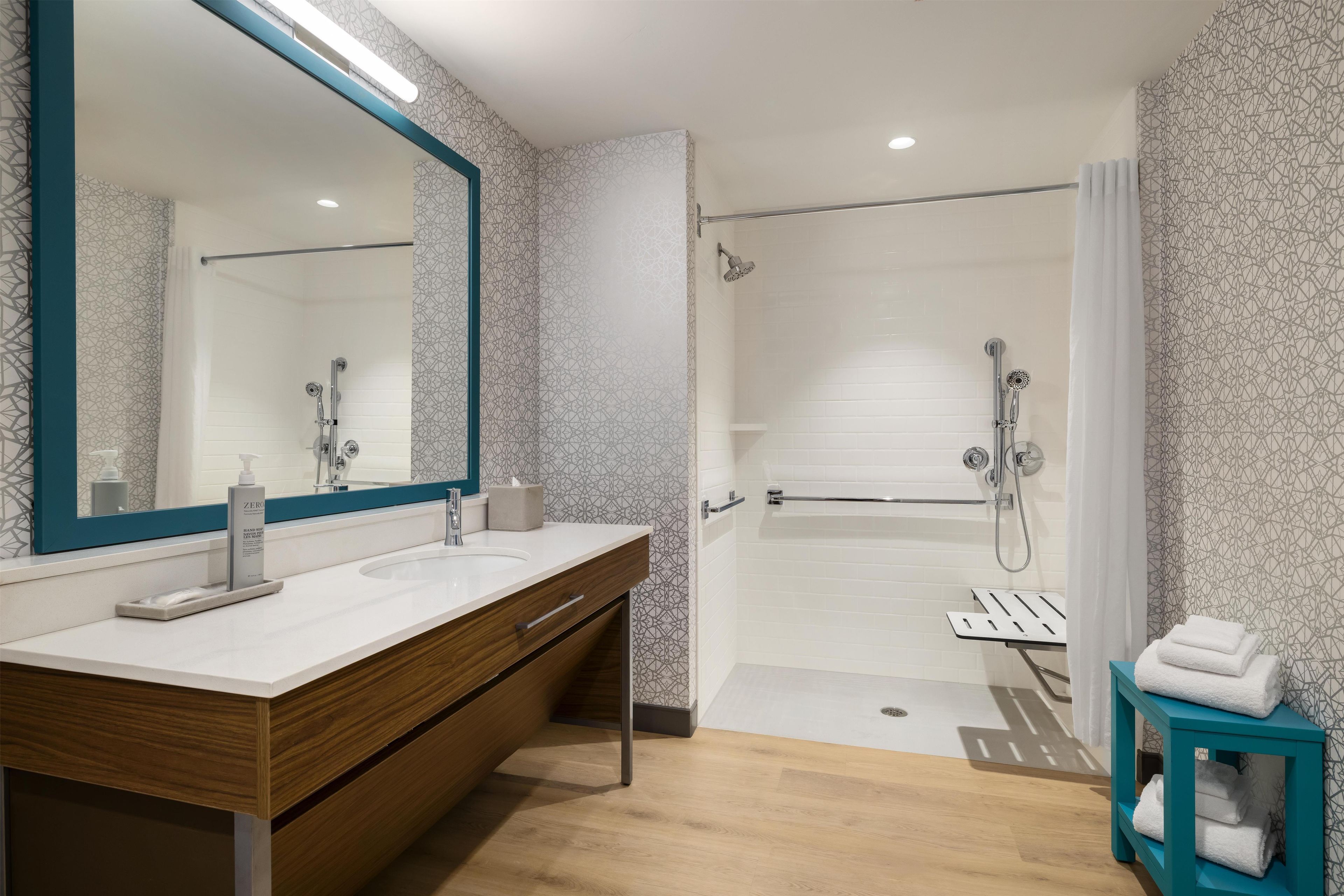 Une salle de bain moderne avec un grand miroir, un lavabo et un espace douche.