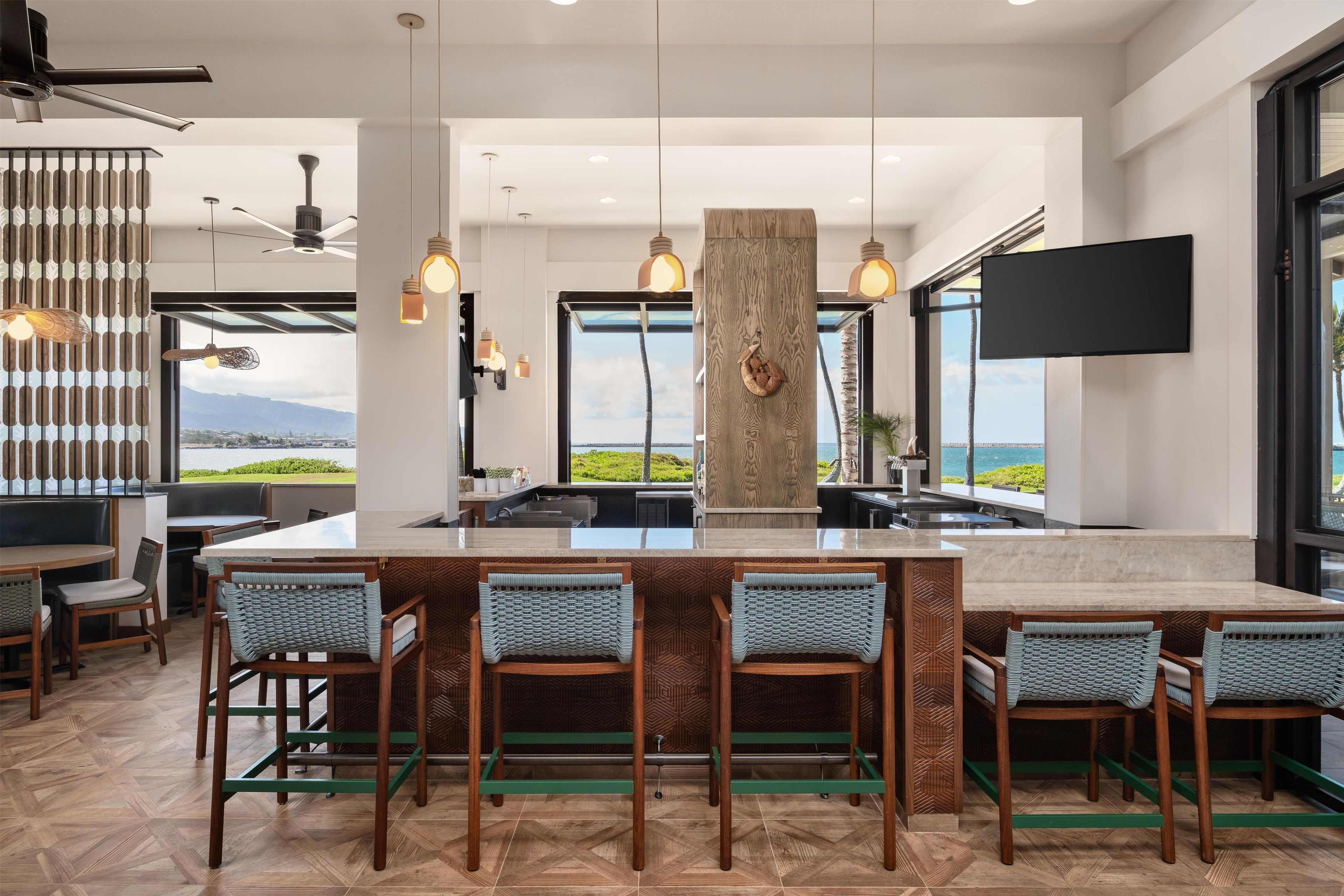 A modern kitchen with a large island, bar stools, and a view of the ocean.