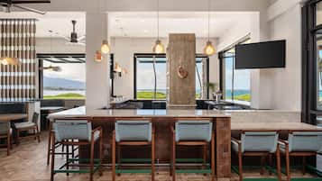 A modern kitchen with a large island, bar stools, and a view of the ocean.