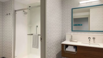 A modern bathroom with a glass-enclosed shower, a vanity with a mirror, and patterned walls.