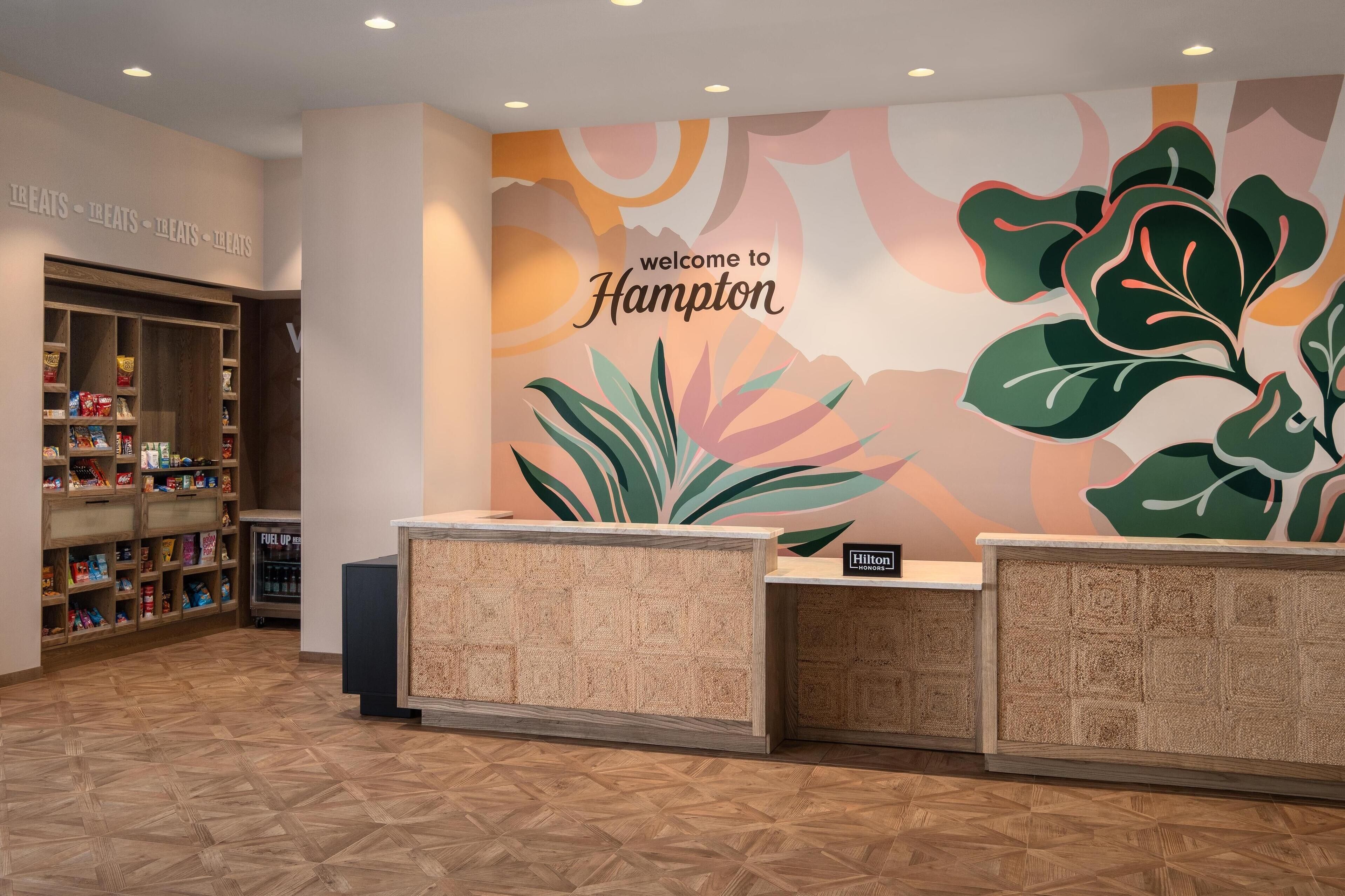 A hotel reception area with a welcome sign, a snack bar, and a reception desk.