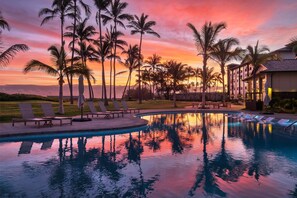 A poolside area with lounge chairs and a building in the background. - Hampton Inn & Suites Maui North Shore (Kahului)