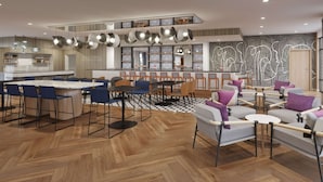 Een moderne hotel lobby met een centraal gelegen bar, zitgedeeltes en een visgraat parketvloer.