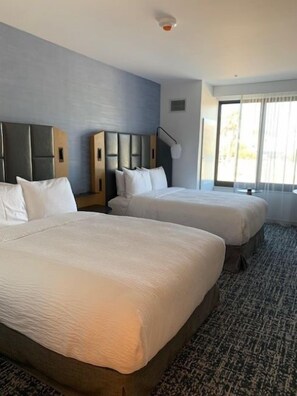 Een hotelkamer met twee bedden, een groot raam en een vloerbedekking.