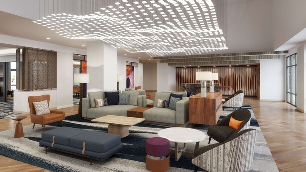 Een ruime lobby met een modern plafondontwerp, comfortabele zithoeken en een groot raam dat zorgt voor natuurlijk licht.
