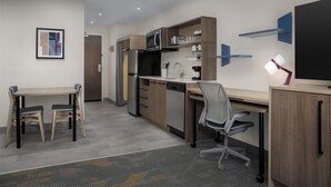 A modern kitchen with a dining table, chairs, a refrigerator, microwave, and a built-in oven. - Home2 Suites By Hilton Tooele (Tooele)