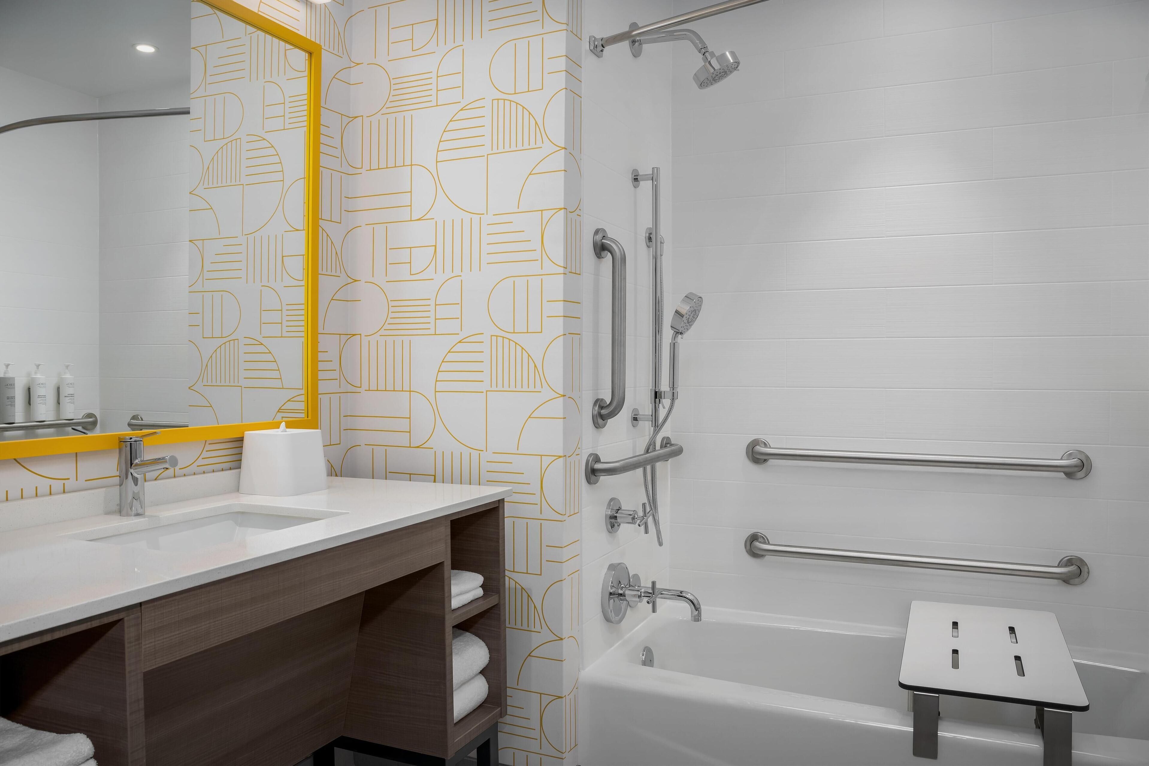 A modern bathroom with a white sink, mirror, and shower area.