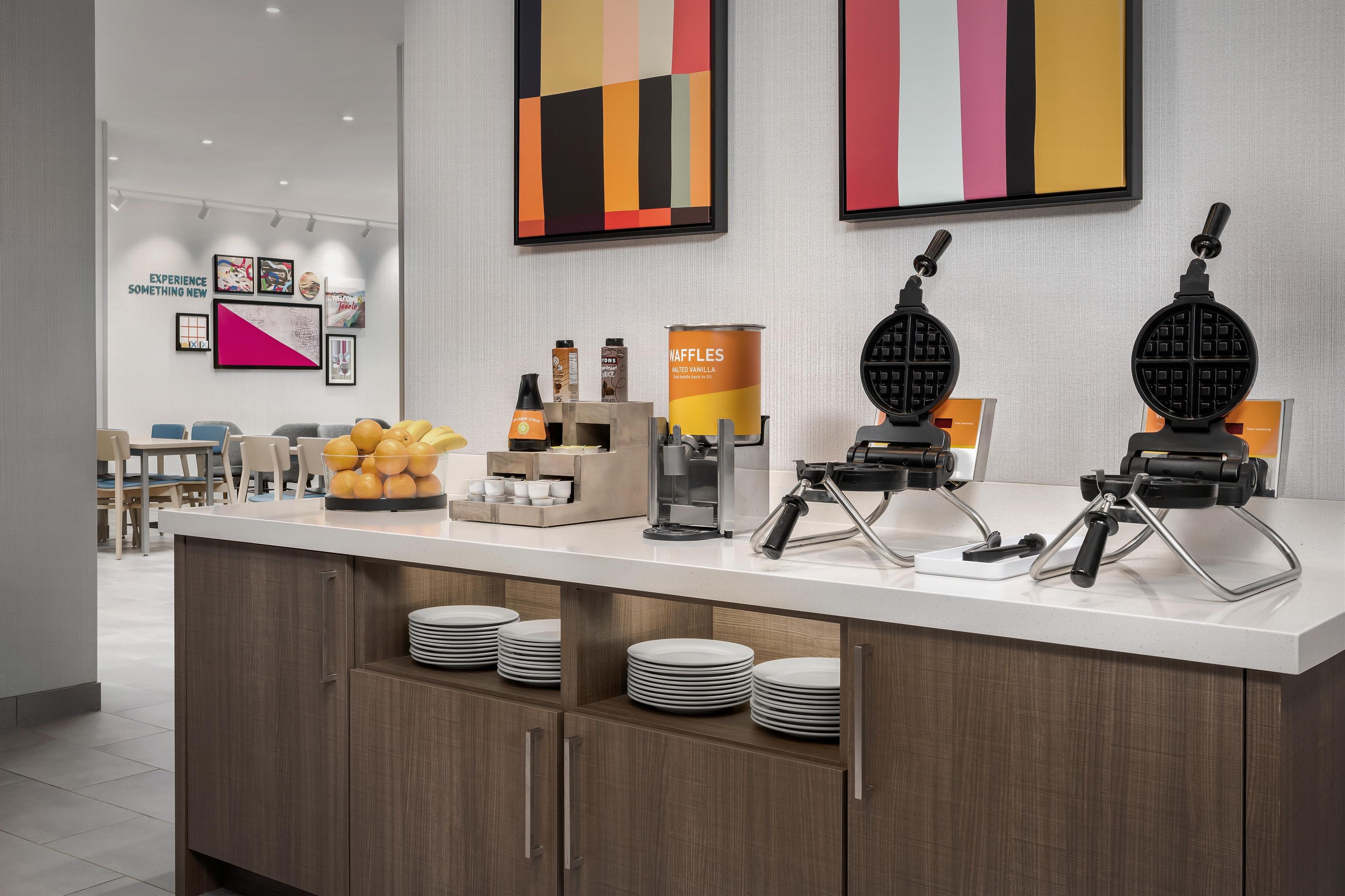 A modern kitchen area with waffle makers, a waffle station, and a coffee machine.
