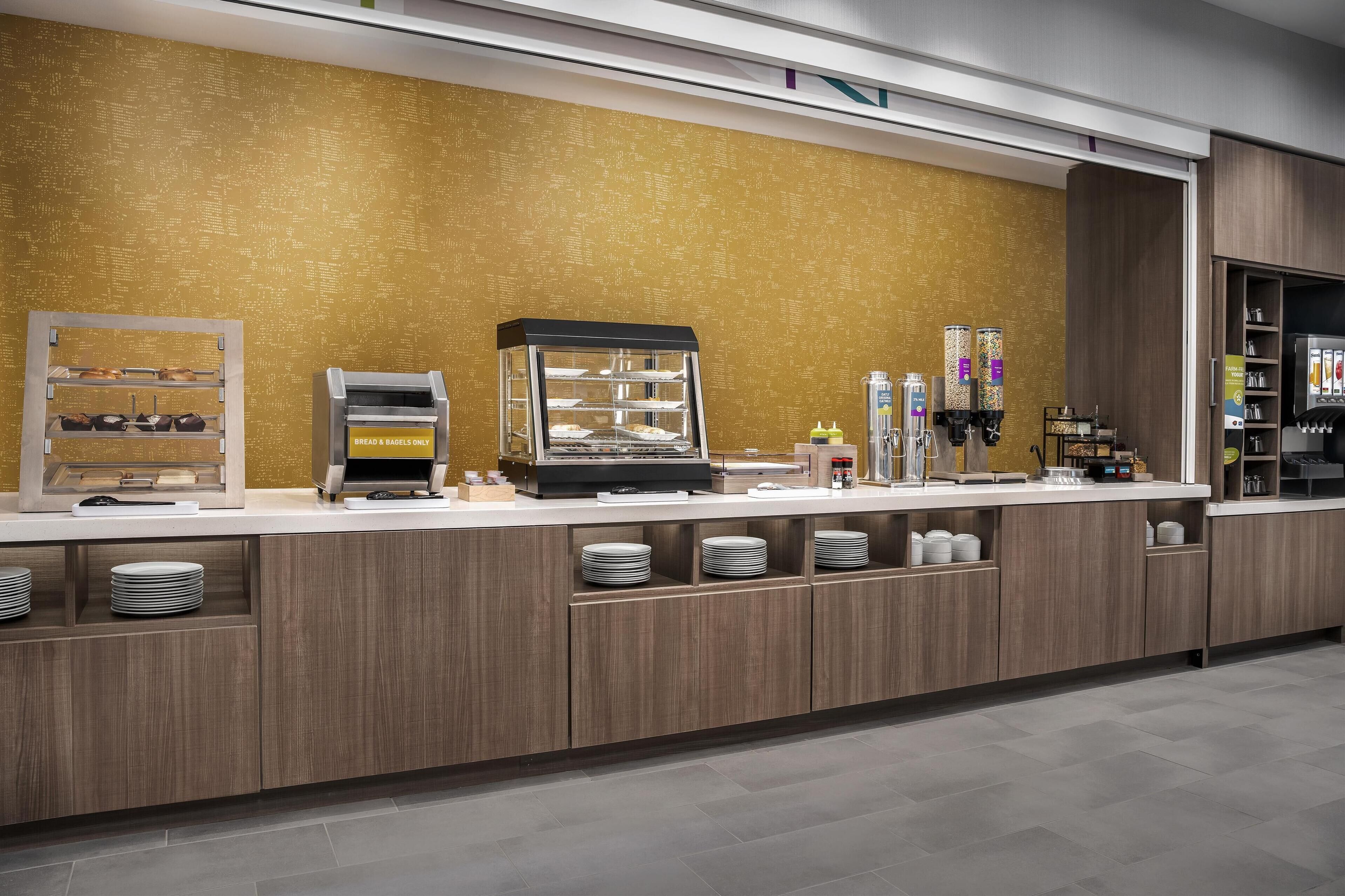Een ontbijtbuffet met een hoek voor brood en eieren, een koffiemachine en drankautomaten.