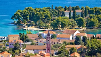 A coastal town with a prominent tower, terracotta-roofed buildings, and a clear view of the sea.