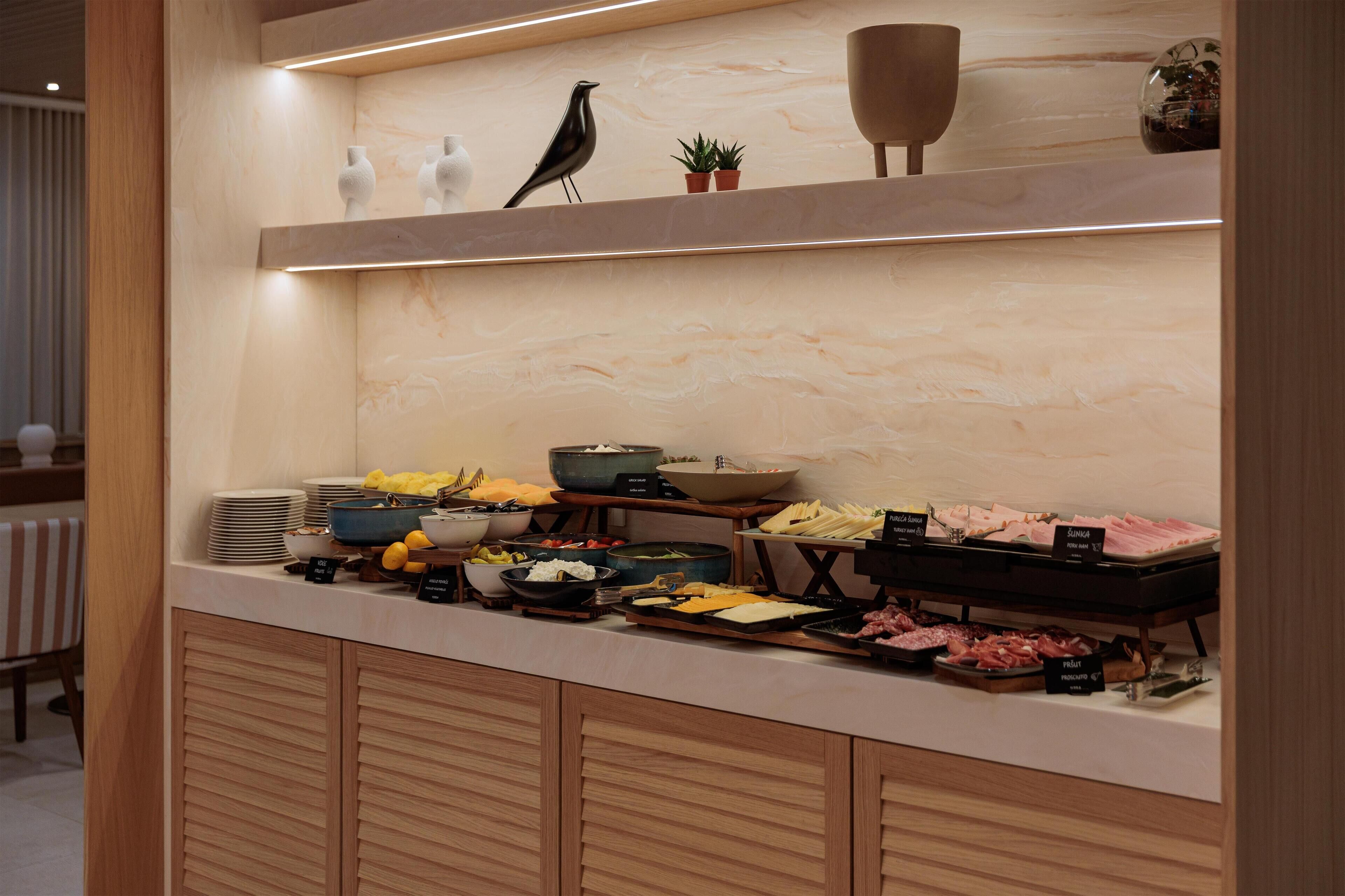 A buffet setup with various food items and a bird perched on the top shelf.