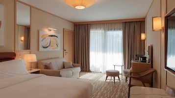 Une chambre d’hôtel avec un grand lit, un canapé, un bureau avec une chaise, une petite table et un téléviseur.