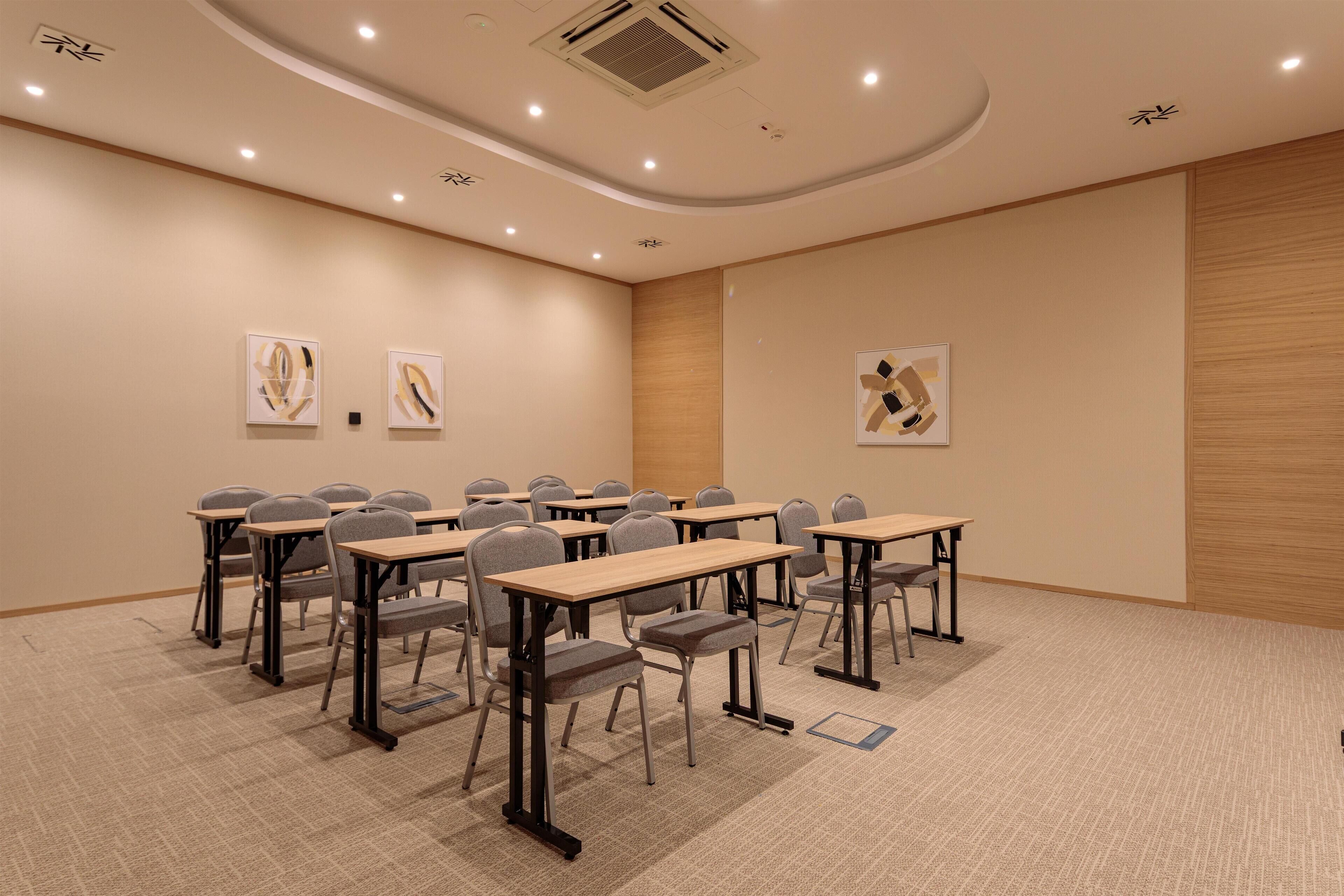 A conference room with multiple tables and chairs, a carpeted floor, and artwork on the walls.