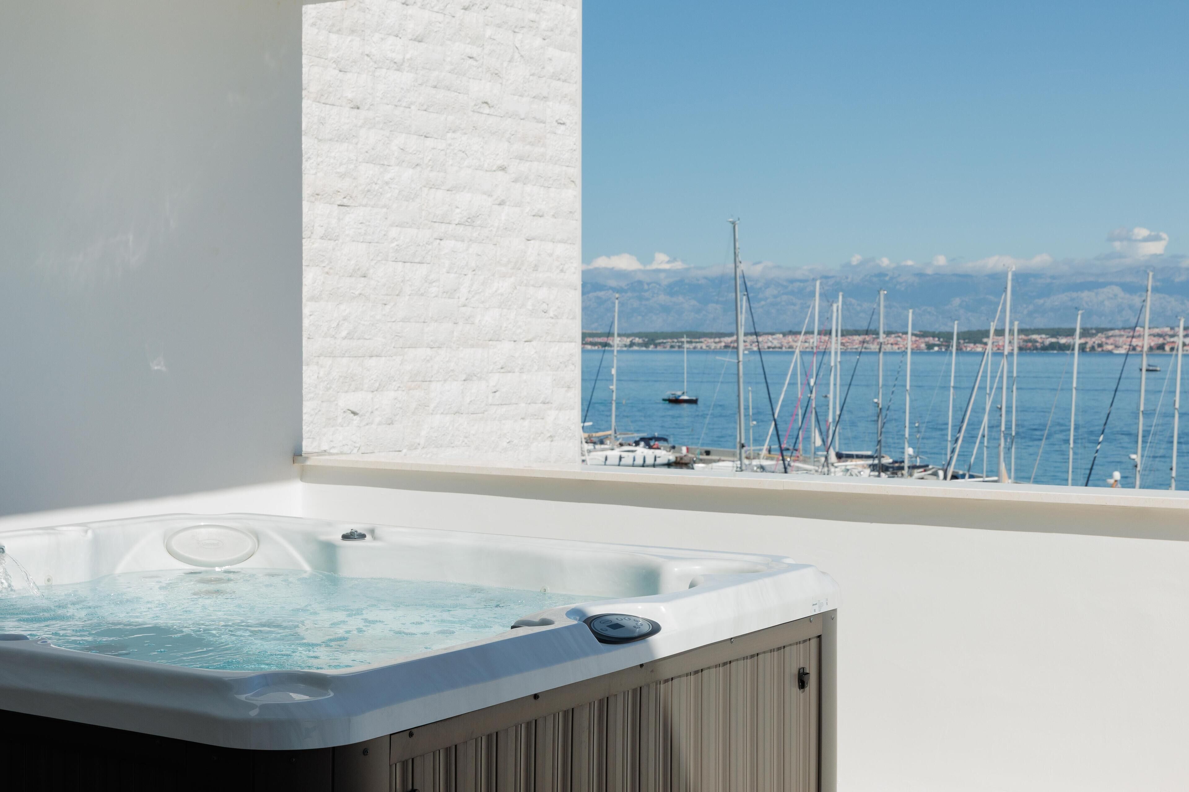 A hot tub with a view of a marina and mountains in the background.