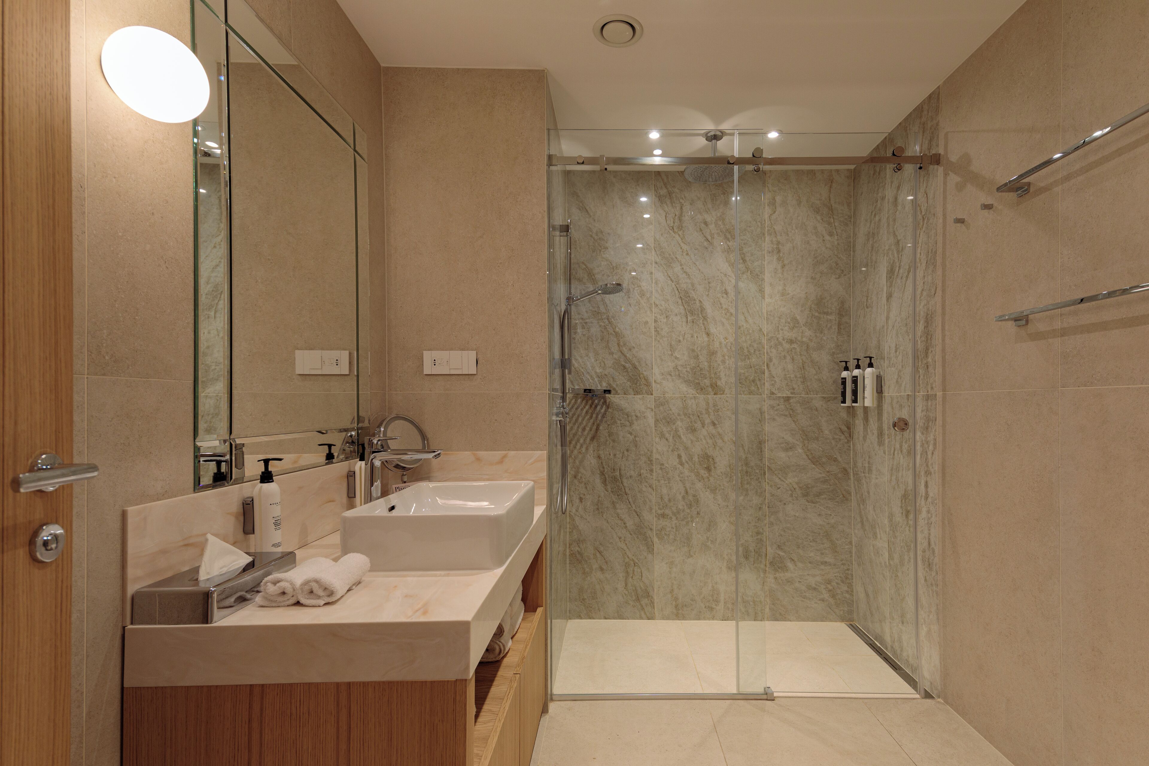 A modern bathroom with two sinks, a glass shower enclosure, and a large mirror.