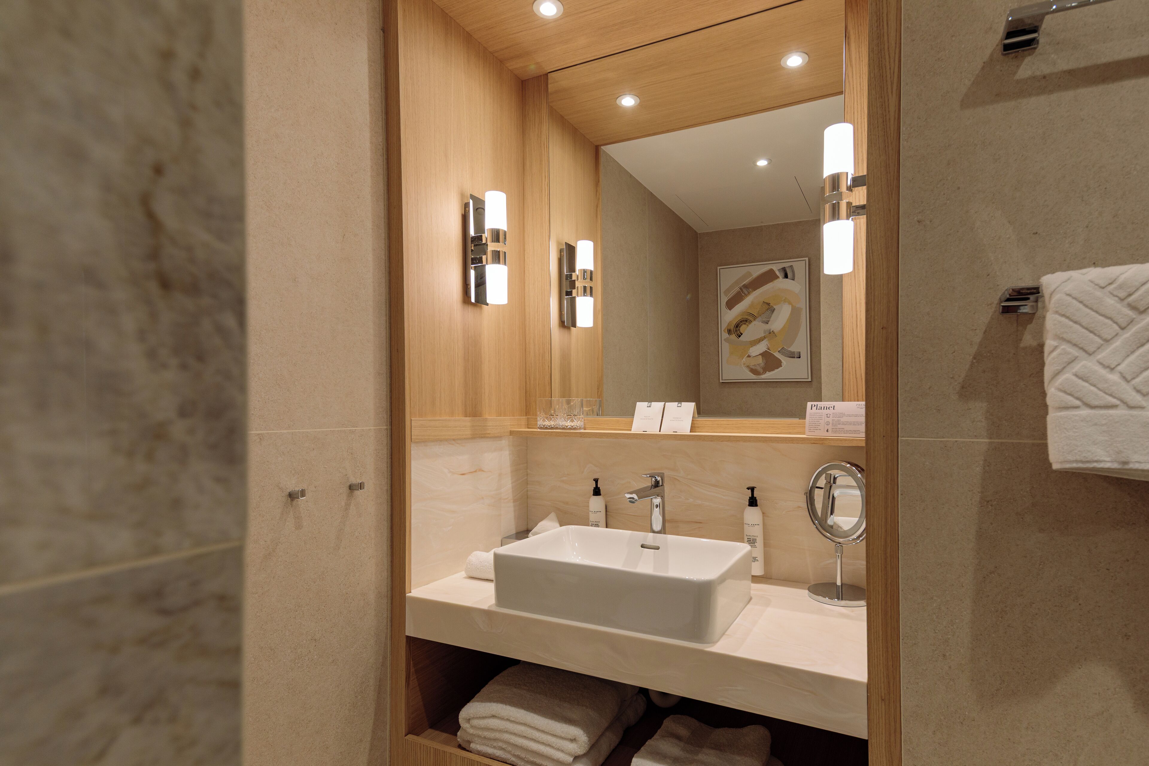 Un baño moderno con un espejo grande, un lavamanos y un perchero para toallas.