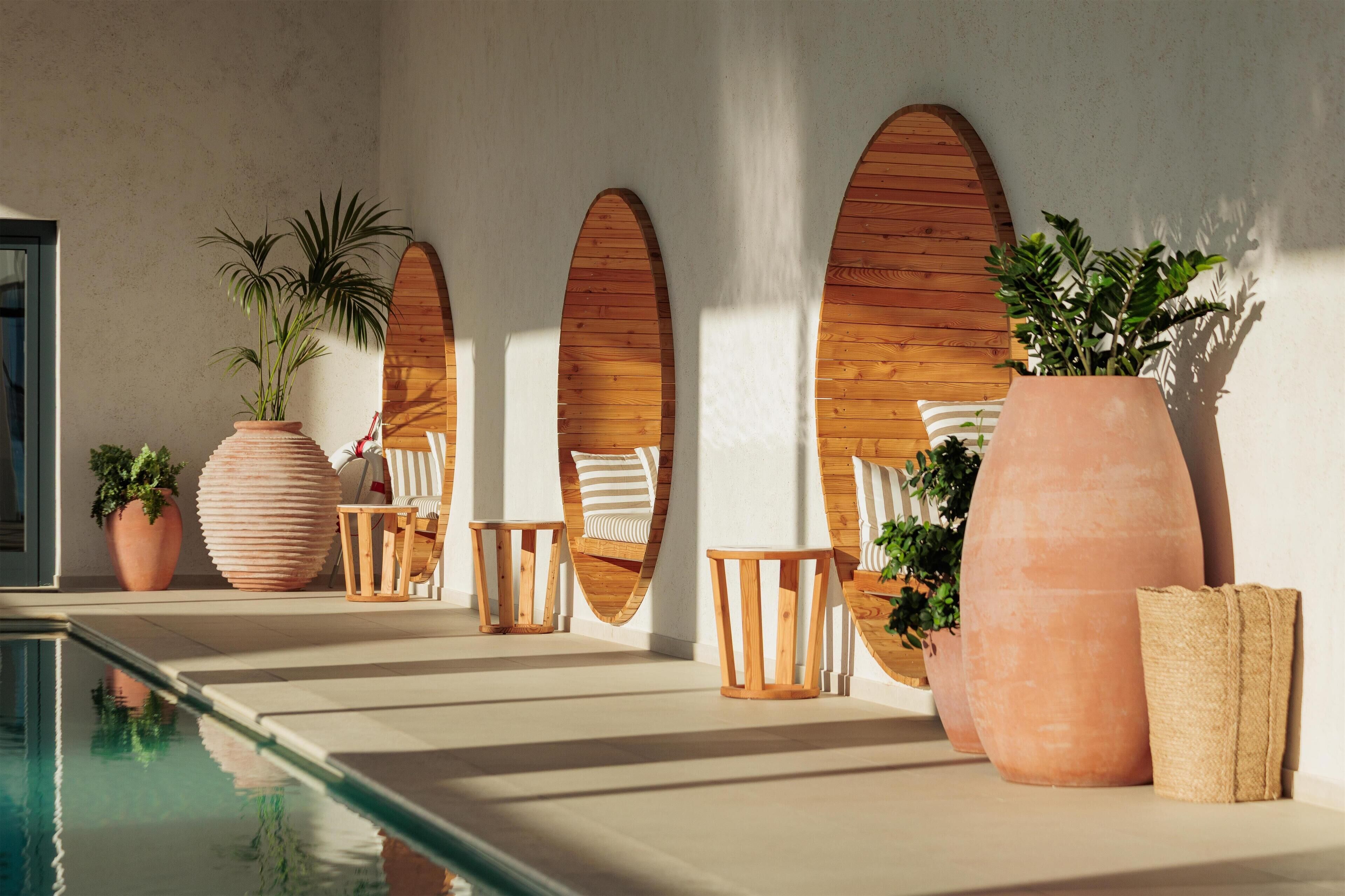 Un espace aménagé au bord de la piscine, avec des jardinières en terre cuite, du mobilier en bois et une conception architecturale moderne.