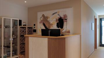 Ein moderner Empfangstresen, eine Vitrine mit Toilettenartikeln und ein großes abstraktes Gemälde an der Wand.