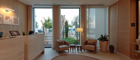 Un hall d’hôtel moderne avec un comptoir d’accueil, deux canapés, une petite table et un grand tapis.
