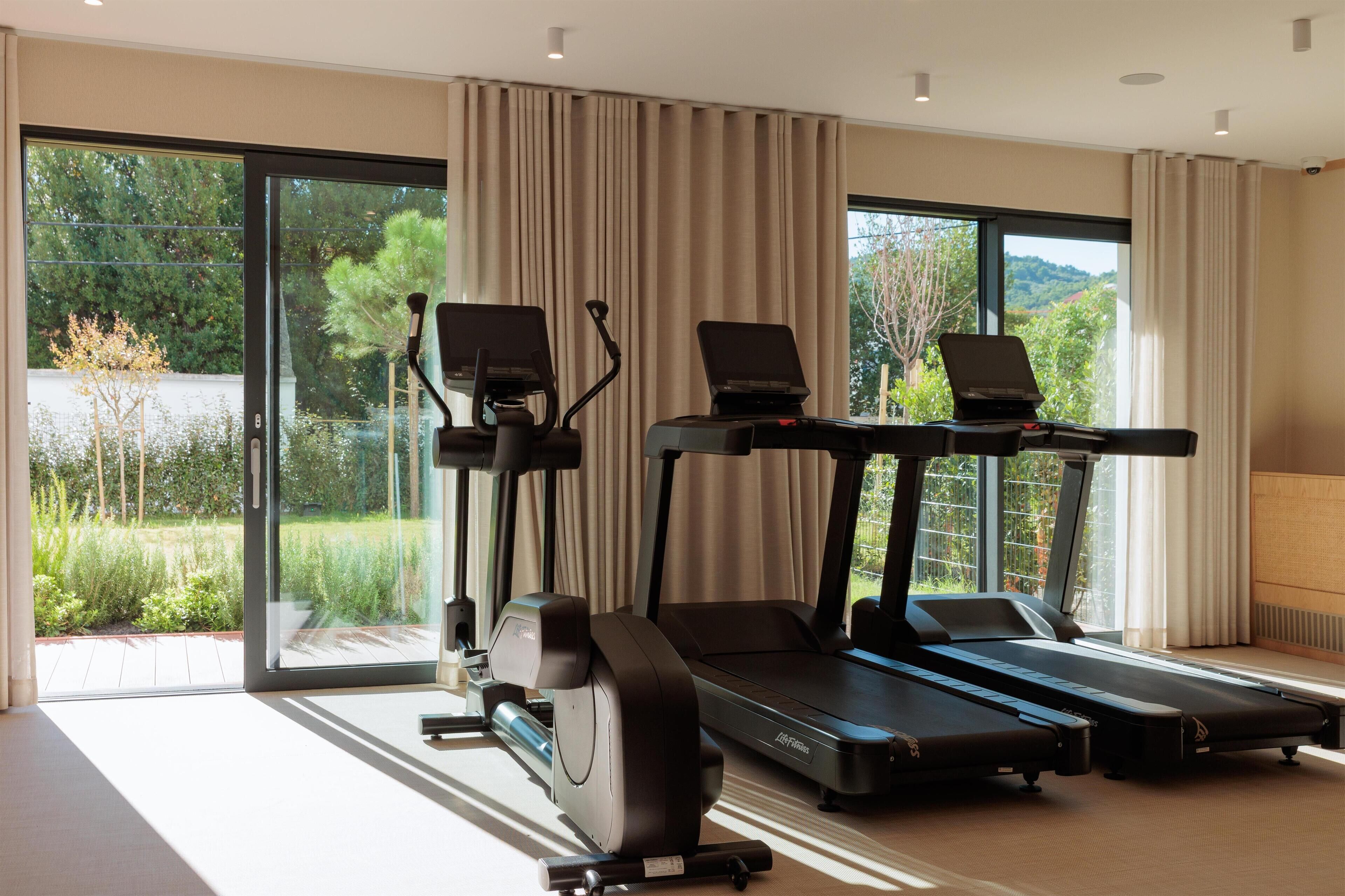 Une salle de sport à domicile équipée de deux tapis de course, d’un vélo elliptique et d’un vélo d’appartement.