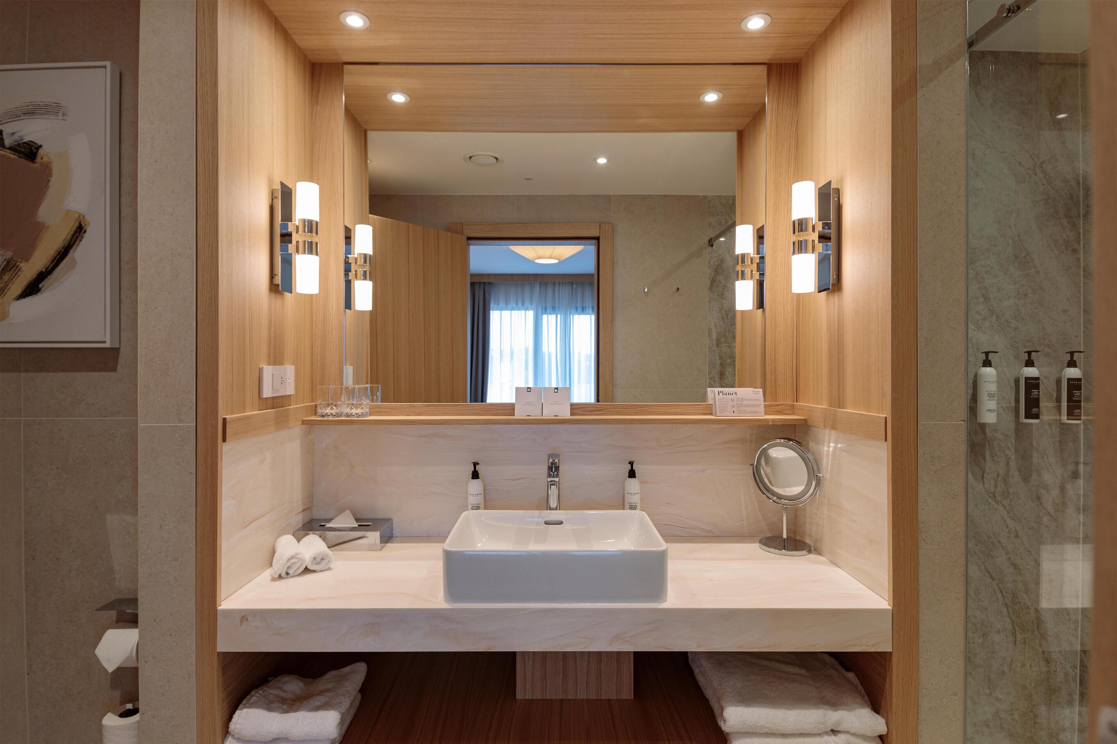 Un baño moderno con un lavamanos grande, dos espejos y una zona de ducha.