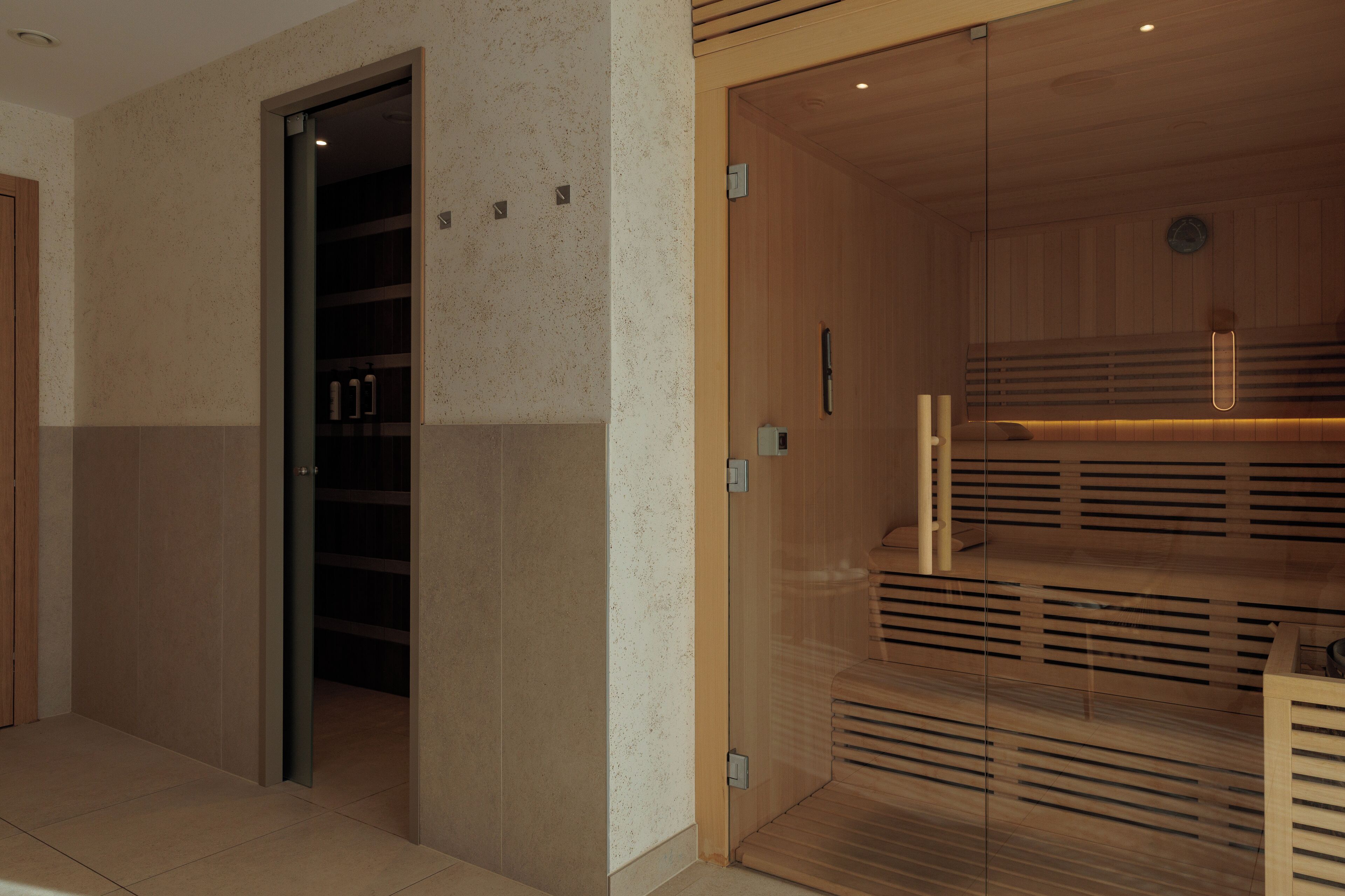 A modern interior with a wooden sauna, a glass door, and a tiled floor.