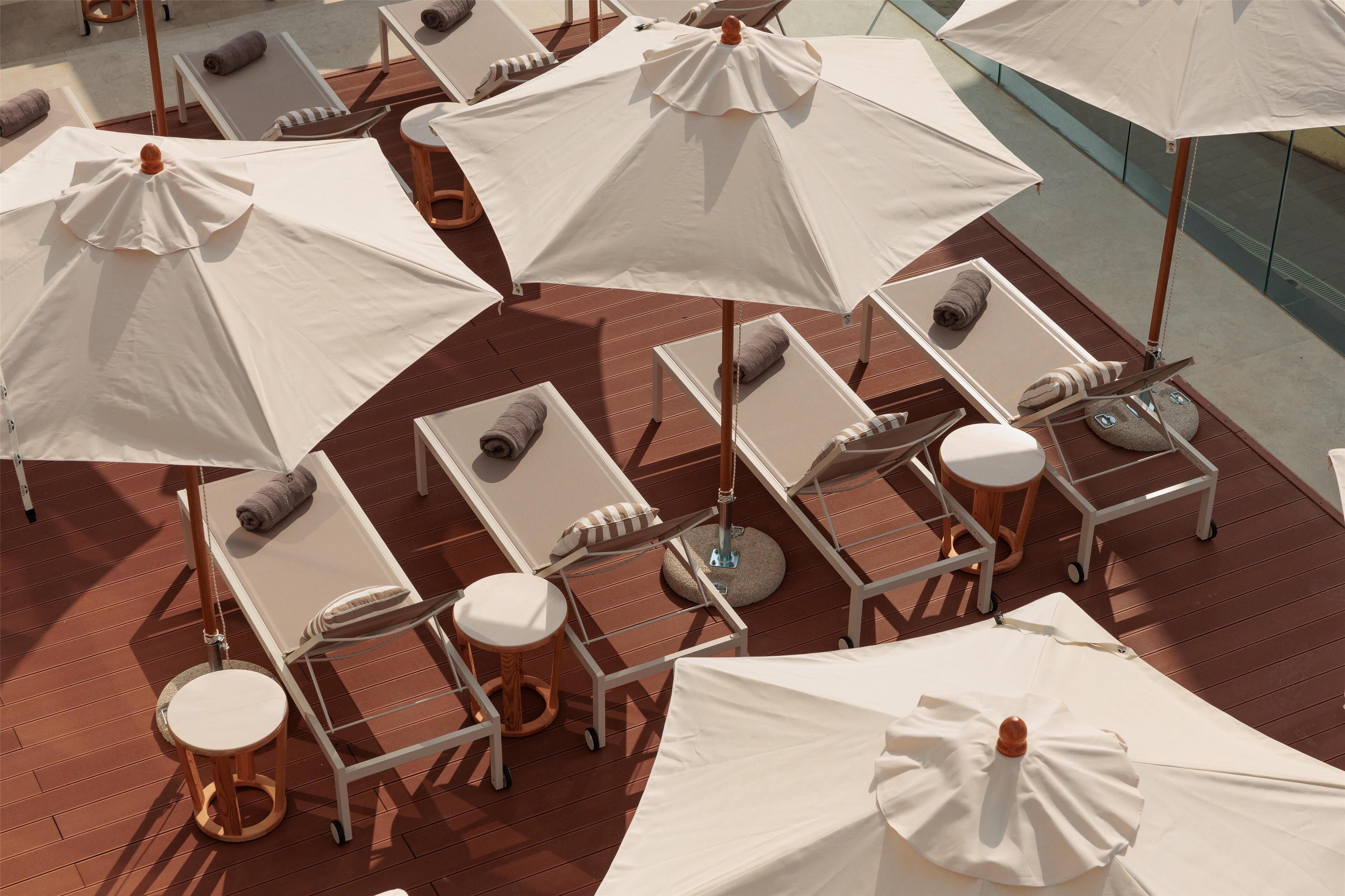 A deck with multiple white sun umbrellas and lounge chairs, some with towels.
