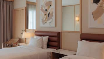 Habitación de hotel con dos camas, una silla, una lámpara y arte abstracto en las paredes.